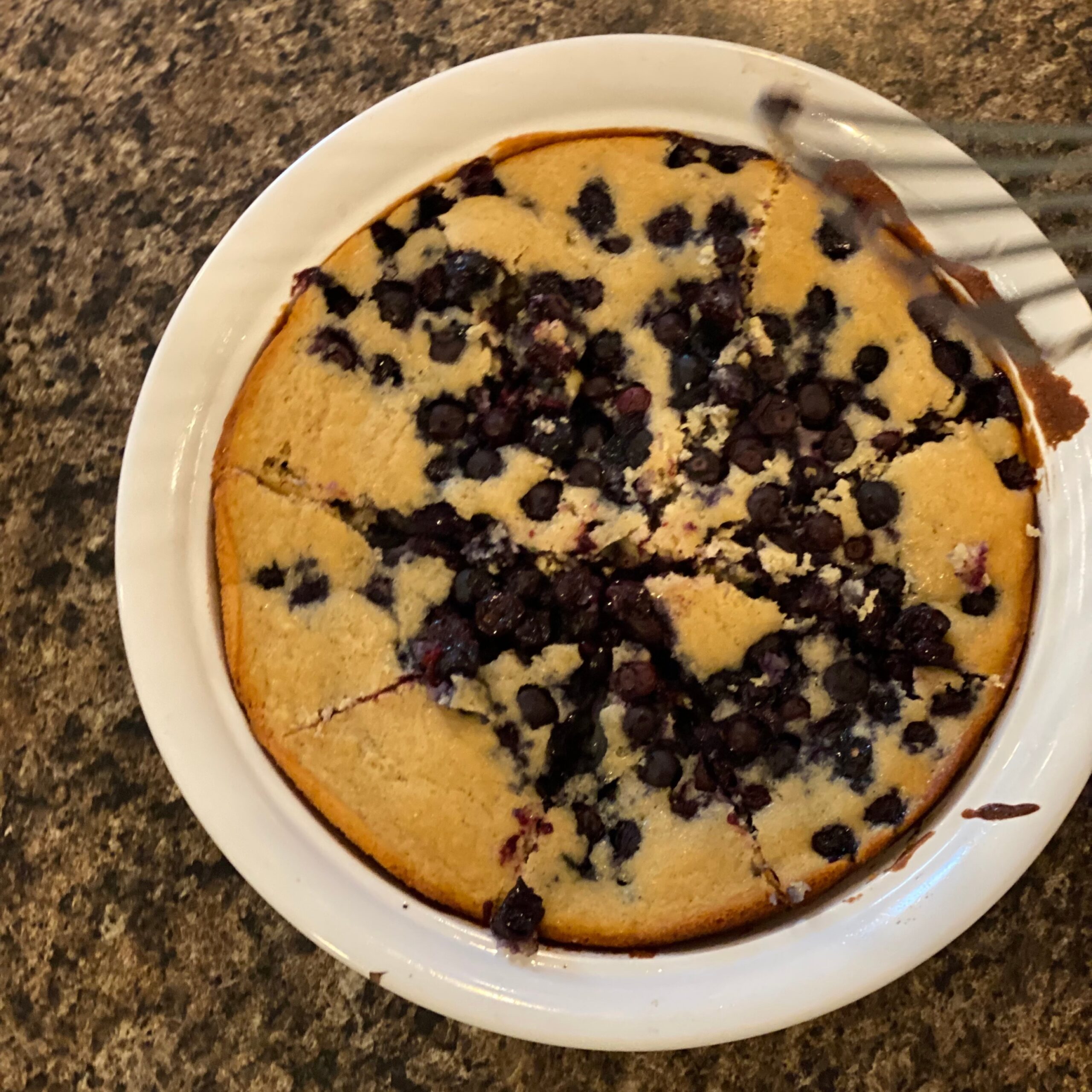 Cobbler with blueberries in a white ramekin on the counter.